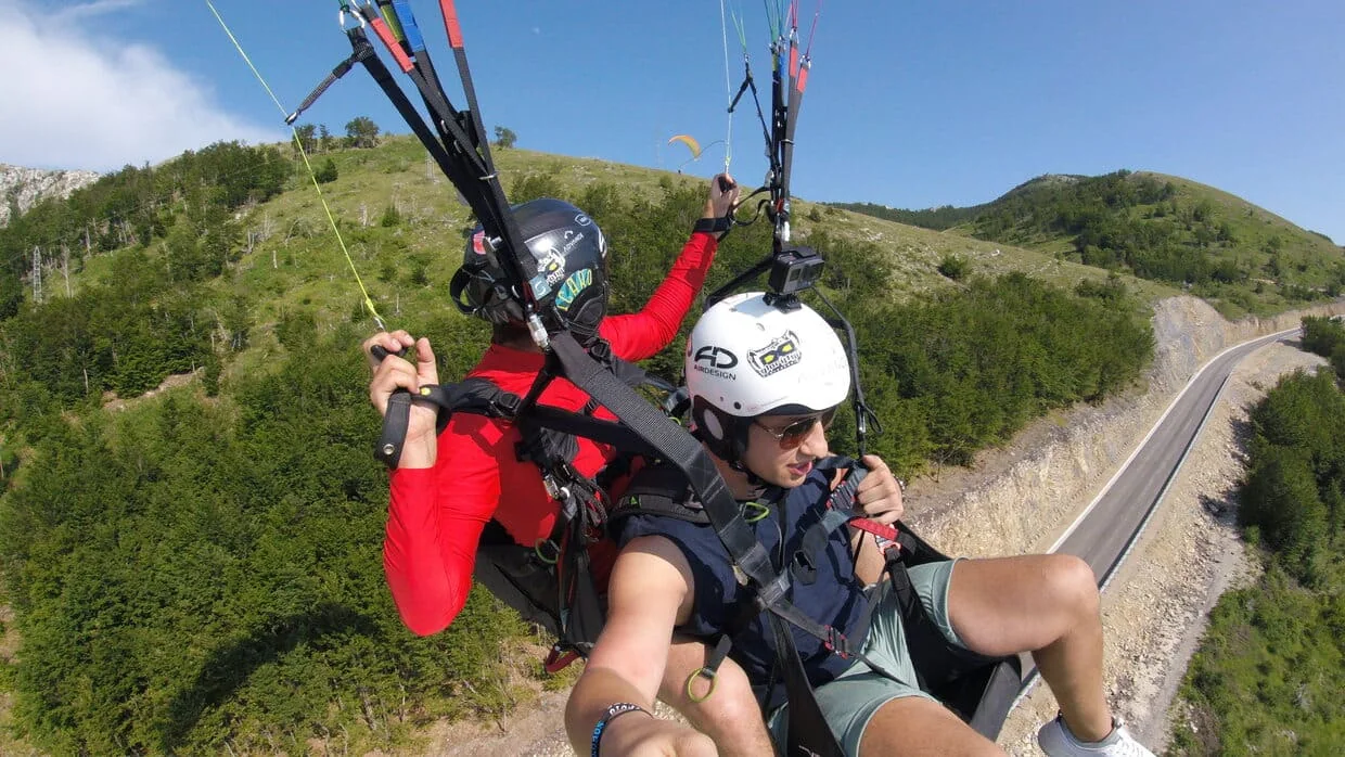 Tandem paragliding passenger and pilot just after takeoff from the Kotor launch.