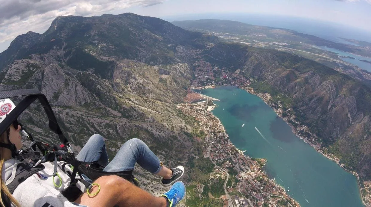 Wide aerial view of the Bay of Kotor, mountains and town from paragliding altitude.