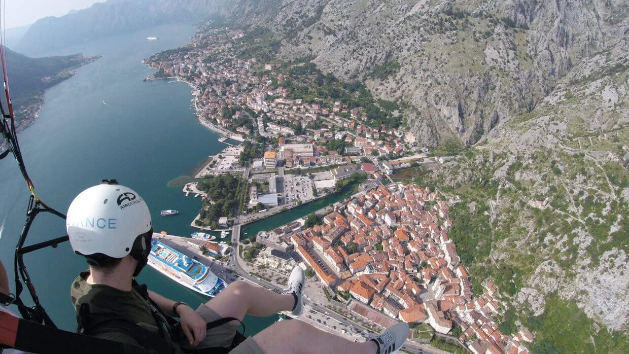 Kotor Old Town and bay shore seen from a descending paragliding route.
