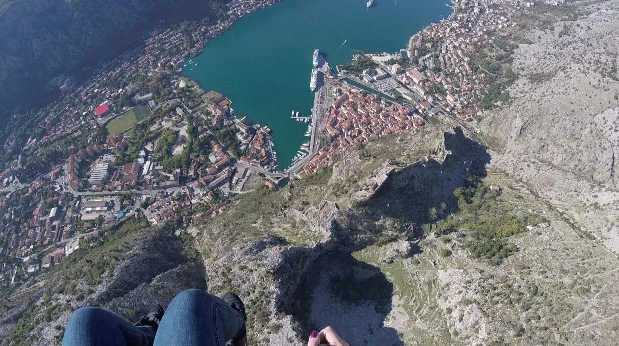 Lower paragliding approach above Kotor Old Town and the bay shore.